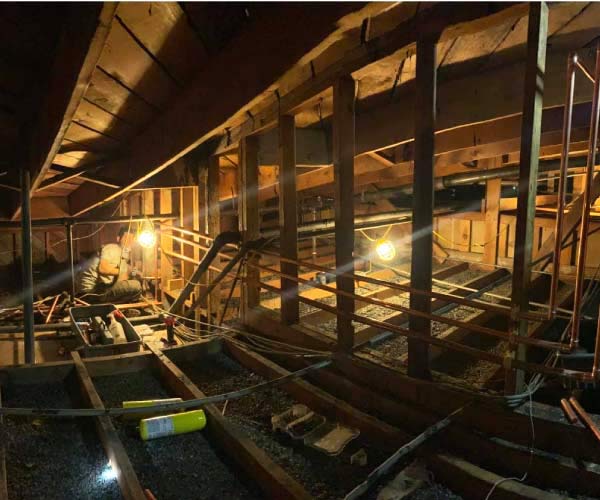 Interior renovation with a plumber Sacramento working amidst exposed beams and pipes.