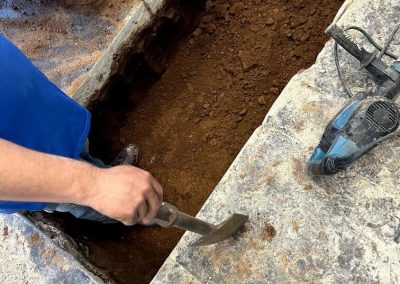 plumber excavating a trench to access a broken sewer line for repair in a residential yard