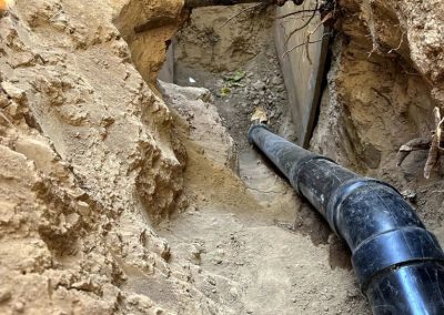 new sewer pipe being lowered into a trench, ready for connection to the existing system