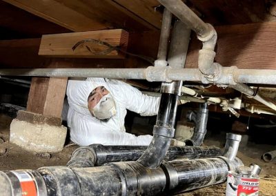 plumber repairing a sewer line beneath a building's foundation, showcasing a complex plumbing job