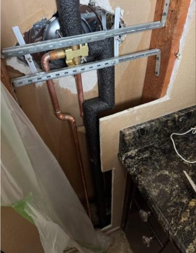 chrome shower valve connected to copper pipes, illustrating the water supply lines for a standard bathroom shower installation