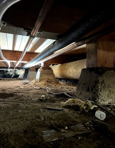 an excavated area showing a section of damaged water line being replaced with new piping