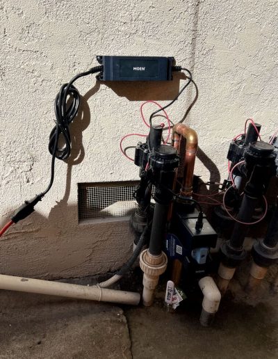 Moen Flo Smart Water Monitor device installed on a main water line, showing its digital display and sensors.