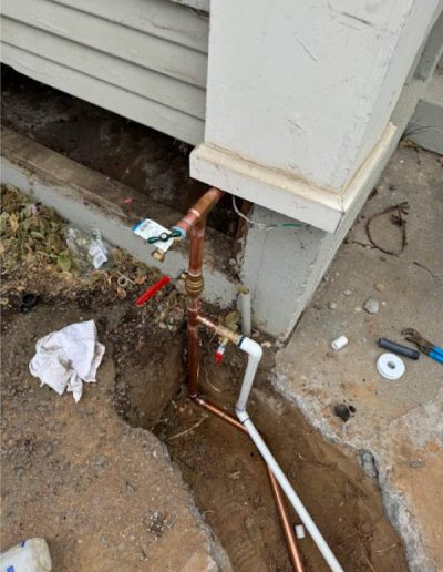 mixed pipe materials (copper and PVC) in a water line repair, revealing the complexity of connecting different plumbing components in a confined space