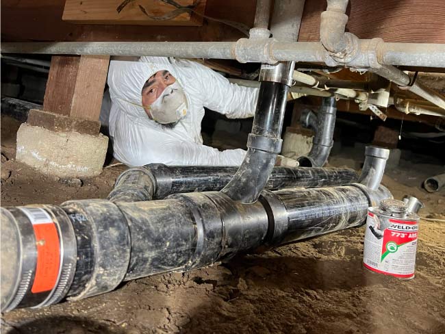 Professional plumber visually inspecting an exposed sewer lateral connection.